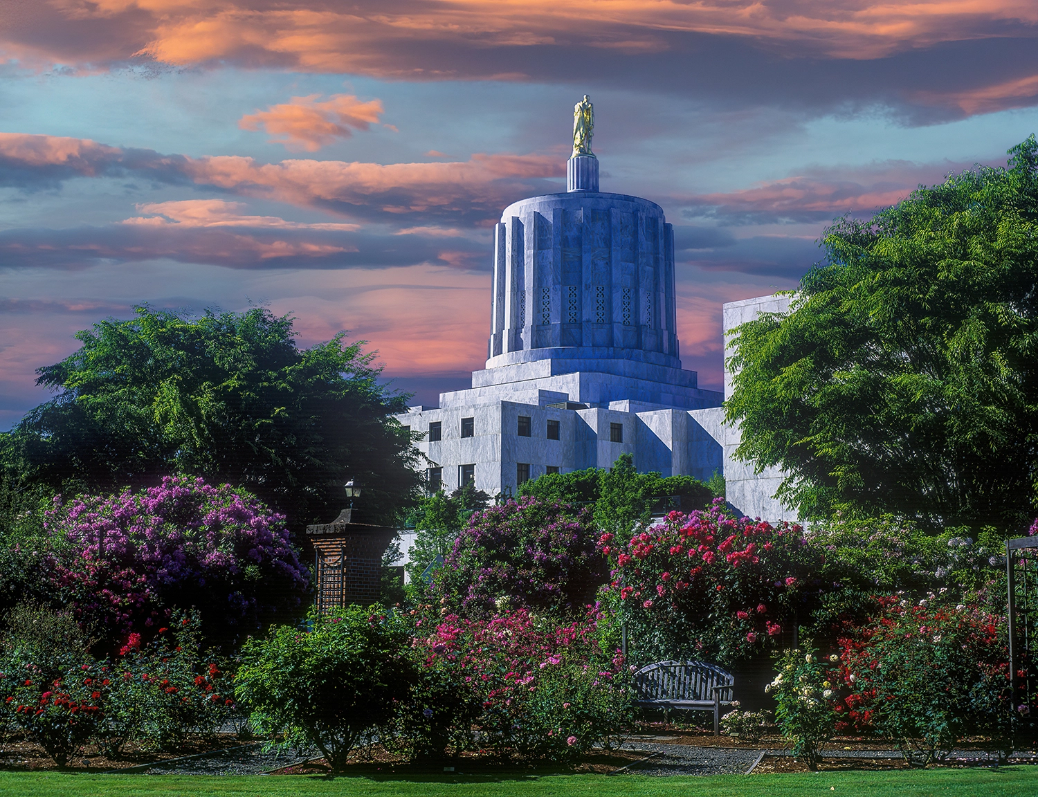 An image of the capitol building in Salem, Oregon surrounded by trees and flowers.